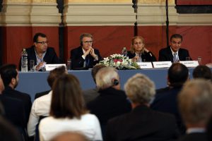 Φωτογραφία από την εκδήλωση με πρόσωπα που μιλούν και παρουσιάσεις