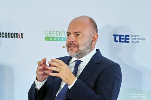 Φωτογραφία του Γιώργου Στασινού, ομιλητής σε συνέδριο, με φόντο το λογότυπο του Green Deal