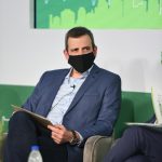 Φωτογραφία του Γιώργου Κοτούλα, Διευθύνοντος Συμβούλου της Ακτωρ, με φόντο το λογότυπο της εταιρείας