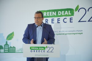 Ομιλία του Σωκράτη Φάμελλου σε συνέδριο για το Green Deal, με φόντο το ακίνητο και το λογότυπο του συνεδρίου